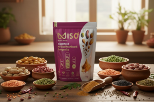 A large, prominent pink and white pouch of MISO powder is centered on a wooden table, surrounded by various ingredients, including several clay bowls filled with different kinds of dried beans, lentils, and peas. The background shows a sunny kitchen counter with potted plants, highlighting the natural, plant-based ingredients of the superfood product.